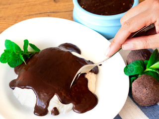 curd jelly with chocolate on a white plate. Female hand holds a spoon