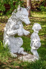 White plaster statue of the fairy tale characters of a gray wolf and a red cap.