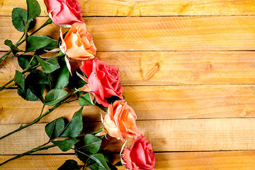 Handmade roses lie on a wooden background. Background layout with free text space.