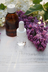 Lilac, syringe essential oil (extract, infusion, tincture) with flower blossoms on white wooden background
