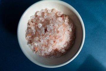 pink salt  in a bowl, blue background. healthy food concept