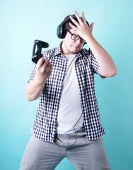 Disappointed young man playing video games holding a joystick isolated on blue background