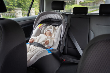 Cute three months old baby sleeping in car seat on back-seat of the car