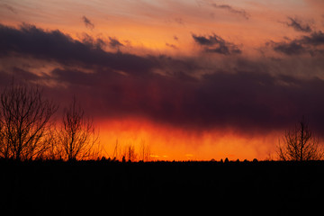 Beautiful fiery bright sunset over the forest and village. Observation of natural phenomena.
