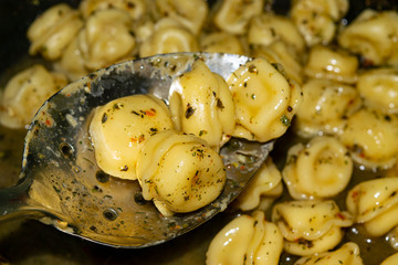 Small dumplings are cooked in a pan with spices. Close up.