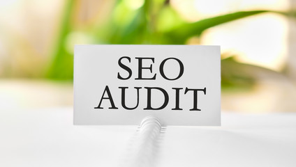 Seo audit - business concept text on a white notebook and green leaves of flowers
