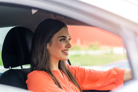 Cute young lady happy driving car. Image of beautiful young woman driving a car and smiling. Portrait of happy female driver steering car with safety belt"n