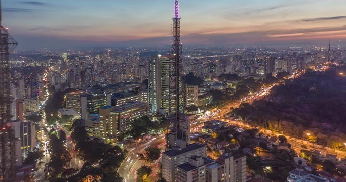 Aerial hyperlapse with heavy traffic, buildings, antennas and sunset with camera in lowering