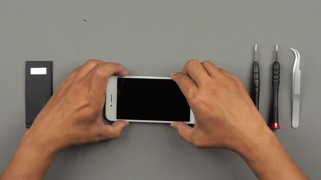 Speed up (time lapse) and top table view (high angle) of technician or engineer using tools for repairing or replace new screen of broken and damaged smartphone on desk. 4K resolution ultra HD