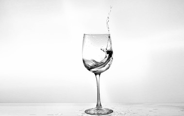 Water in a wine glass. Splash of liquid on a white background. Isolated object. Spray. Selective focus.