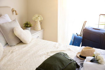 Holiday hotel room with suitcases and hand luggage on bed