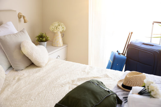 Holiday Hotel Room With Suitcases And Hand Luggage On Bed