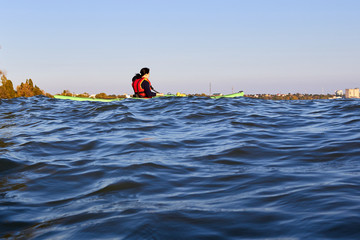 Woman rowing on green kayak on a Danube river in deep blue water
