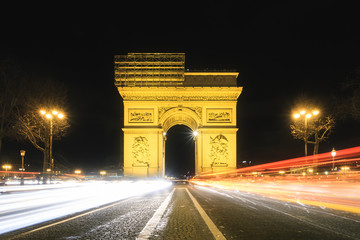 Beautiful cityscape urban street view of the Arc de Triomphe in Paris, France, on a spring evening after sunset at night, seen from the Champs-Elysees with traffic