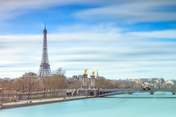 Beautiful cityscape of the river Seine with the Pont Alexandre III bridge and the Eiffel tower in Paris, France, with clouds in spring