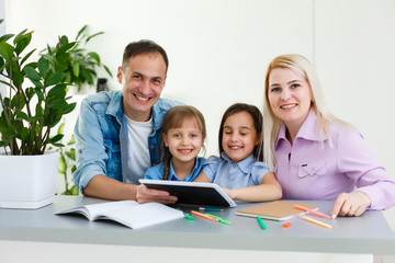 Happy family of four parents and cute little kids children enjoy using the tablet, watching cartoons, make internet video call or shopping online looking at computer screen sit together at home