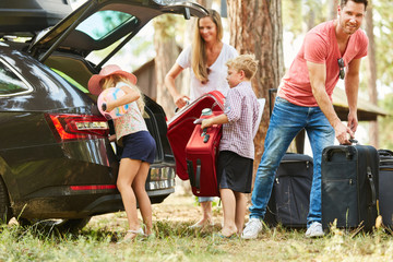 Family at the suitcase packing at the car