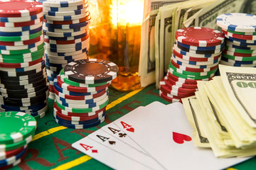 Dollar bills, casino chips and whisky glass on table. Gambling game concept.