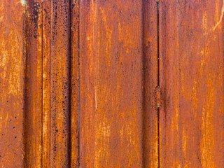 Texture of orange rust on the gate. Illuminated by the orange setting sun.