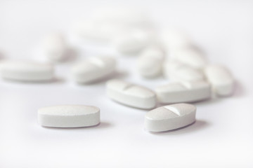 White pills on a white background close-up. Painkillers. A remedy for the Covid19 virus. Tablet macro. Copy space.