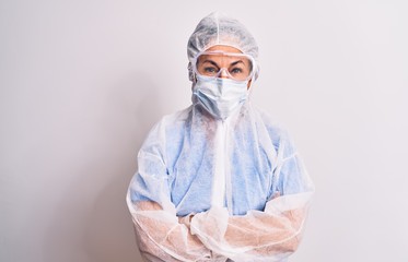 Middle age nurse woman wearing protection coronavirus equipment over white background happy face smiling with crossed arms looking at the camera. Positive person.