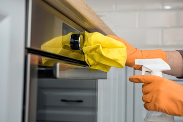 Man's hand in gloves cleaning the kitchen oven