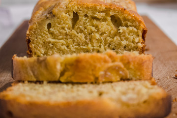 Homemade sliced healthy banana bread ready for serve on breakfast on the white concrete background with craft baking paper and pastry knife, glass of milk. Top view. Close up shoot