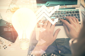 Double exposure of man's hands typing over computer keyboard and bulb hologram drawing. Top view. Idea concept.