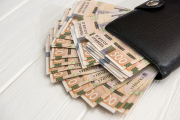 UAH, Black men's wallet is full of money. UAH Money of Ukraine 1000 and 500 banknotes on desk