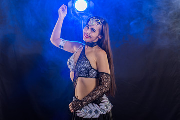 Young woman belly dancer in exotic dress with gold, dancing tribal fusion dance in studio.