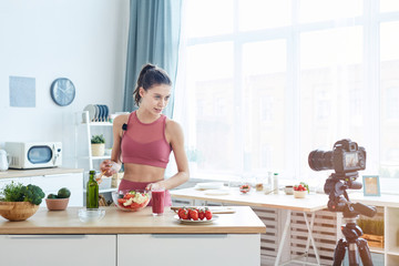 Waist up portrait of fit young woman talking to camera while recording cooking video on healthy food, copy space