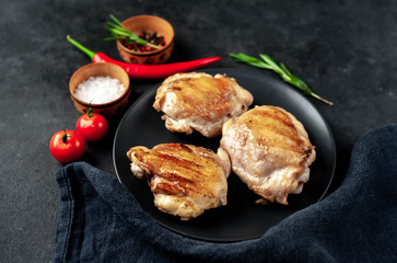 Skinless grilled chicken thighs with spices on a stone background