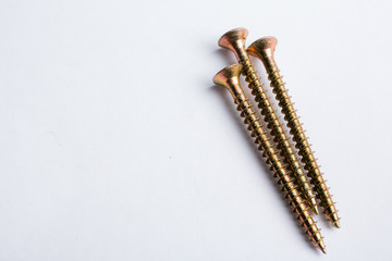 Three yellow zinc-plated wood screws lie on a white background. Close-up. Repair concept