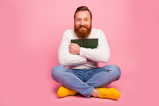 Full size photo of cheerful candid guy sit floor legs folded hug his favorite book wear warm cozy comfort jumper pullover jeans isolated over pastel color background