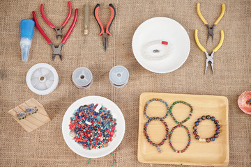 Fototapeta na wymiar Pliers, wire cutters, beads and tray with handmade gemstone bracelets on table