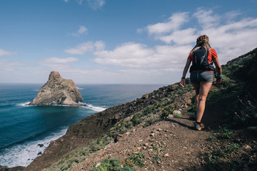 Woman runs cross country on a path in mountain path at Canary Island. Ocean view