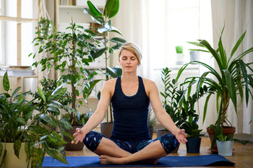 Front view of young woman indoors at home, doing yoga exercise.