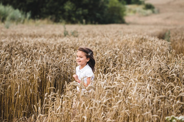 Close up of happy girl with long blonde hair running to the camera through barley field.