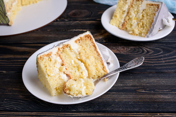 Delicious biscuit cake with coconut impregnation, pineapple slices, cut. Cake on white dishes, on the table. View from above.