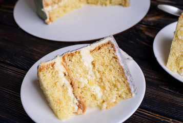 Delicious biscuit cake with coconut impregnation, pineapple slices, cut. Cake on white dishes, on the table. View from above.