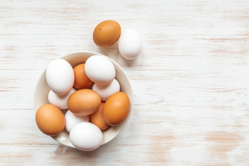 Free-range organic brown and white eggs in bowl on wood background with copy space