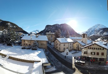 Sankt Moritz (Schweiz) Berglandschaft mit Schnee im Winter bei Blauem Himmel in den Alpen mit Sicht auf ein kleines Dorf, mit Schnee bedeckten Dächern und einer Kirche und Alpen mit Hotels und Straße