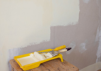 water-based paint in containers and a brush on the background of a painted wall