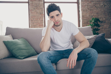 Fototapeta premium Portrait of his he nice attractive depressed dumped guy sitting on divan feeling bad after party waiting friends at modern industrial loft brick interior style living-room