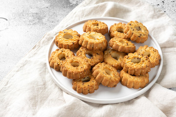 Shortbread cookies in a large white ceramic plate on the light gray kitchen table. A lot of cookies in the plate. Homemade delicious pastries