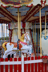 Old carousel in a holiday park. Horses and airplane on a traditional fairground vintage carousel. Merry-go-round with horses.