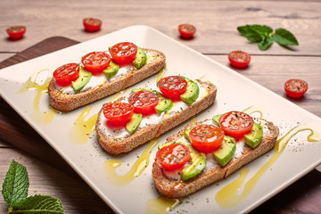 Fototapeta na wymiar Healthy food, tomato and avocado toasts on a wooden cutting table.