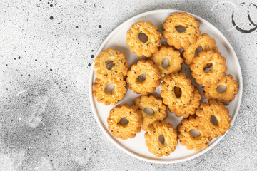 Shortbread in a large white ceramic plate on the light gray kitchen table. There are a lot of cookies in the plate. Homemade delicious pastries. Top view with space for text