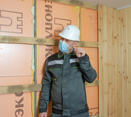 Construction worker wearing a medical mask, uniform and white helmets to protect against coronovirus