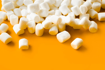 Small white marshmallows scattered on a yellow background